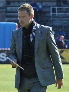 Magnus Pehrsson i grå kostym och halsduk på en fotbollsplan 2011