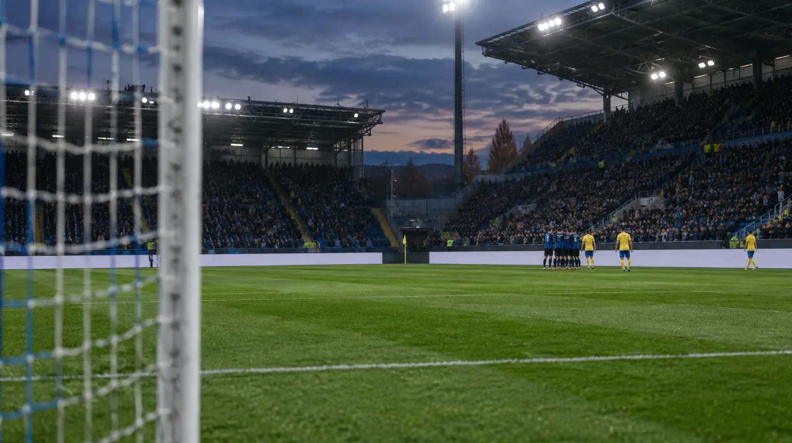 Spelare jublar tillsammans vid hörnflaggan i kvällsljus